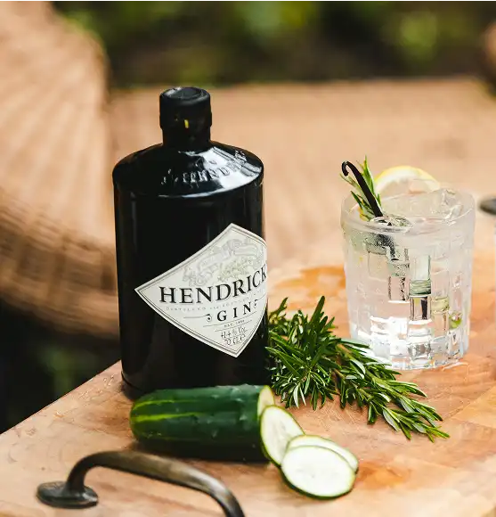 boca hendrick's gina kraj koje je čaša gin-tonica ukrašena ružmarinom i limunom. izrezan krastavac i ružmarin na dasci