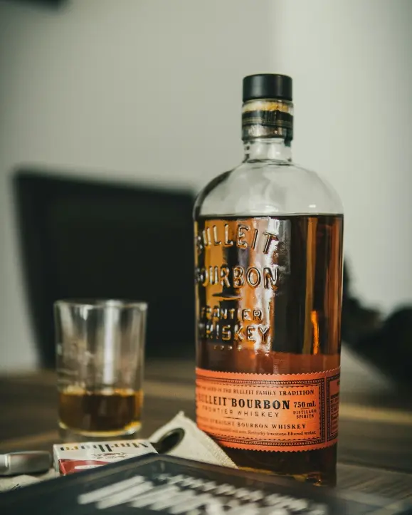 Boca Bulleit bourbon sa čašom na stolu