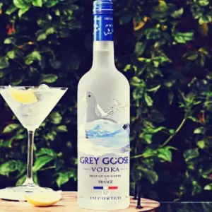 Boca Grey Goose votke na stolu pokraj čaše na stalku sa pićem i ledom u njoj