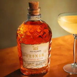 Boca Old St. Croix A.H. Riise ELIXIR Orange Grove Liqueur rum likera na stolu pokraj čaše na stalku sa koktelom