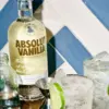 boca Absolut Vanilia Flavored Vodka 0,7l u elegantnoj boci okruženoj čašama s koktelima, ledom i kriškama limete na ljetnoj barskoj sceni
