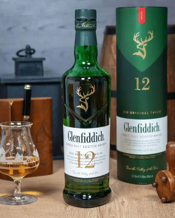 Boca Glenfiddich 12 years old scotch single malt whisky na stolu, pokraj poklon kutije i čaše sa viskijem