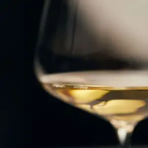 Elegantna čaša za bijelo vino s blijedo zlatnim vinom i naglašenim kristalnim sjajem na tamnoj pozadini