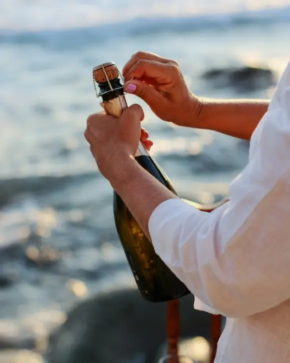 otvaranje boce pjenušca uz more. prosecco, champagne ili cava